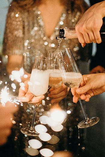People toasting with champagne glasses amidst sparklers at a festive party. HD phone wallpaper