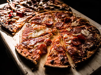 Delicious crispy pepperoni pizza slices on a wooden board, perfect for pizza lovers. HD wallpaper