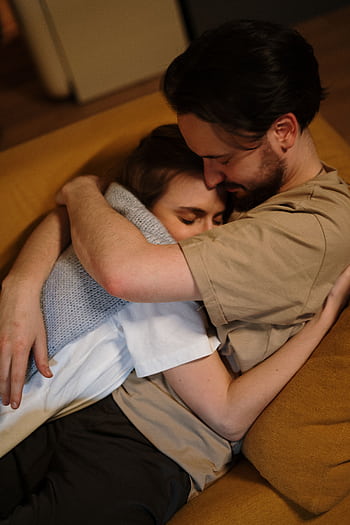 A loving couple embraces warmly on a sofa in a cozy home setting. HD phone wallpaper