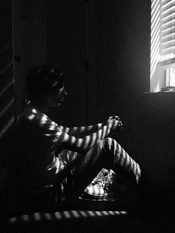 Black and white of a thoughtful man sitting by a window with blinds casting shadows. HD phone wallpaper