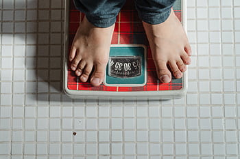 Top view of a child barefoot on a bathroom scale on a tiled floor. HD wallpaper