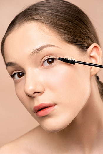 Close-up of a young woman applying mascara to enhance her eyelashes. HD phone wallpaper