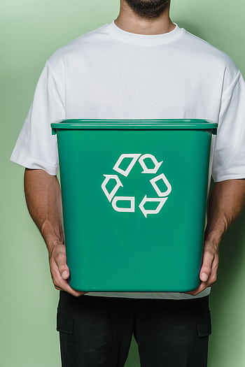 Adult male holding a green recycling bin against a green background, promoting sustainability. HD phone wallpaper