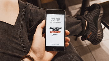 Hand holding displaying motivational quote. Casual setting with sneakers visible. HD wallpaper