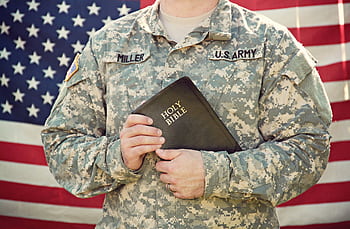 American soldier in uniform holding the Holy Bible, symbolizing faith and patriotism. HD wallpaper