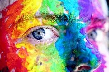 Close-up of a person with colorful rainbow face paint, symbolizing LGBT pride and expression. HD wallpaper