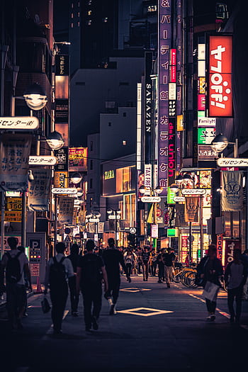 Bustling street in Tokyo at night filled with neon signs and people enjoying the lively atmosphere. HD phone wallpaper