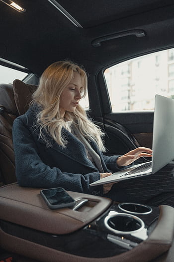 Businesswoman working remotely on a laptop in the backseat of a luxury car. Stylish, modern, and focused. HD phone wallpaper
