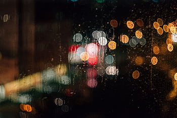 Abstract of city lights creating a bokeh effect on a rainy night through a wet window. HD wallpaper