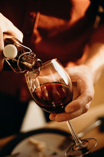 Close-up of pouring red wine into a glass, perfect for restaurant or romantic dinner themes. HD phone wallpaper