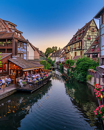 Scenic view of a que canal with half-timbered houses in Colmar during sunset. HD phone wallpaper