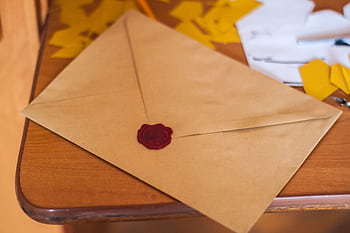 A close-up of a vintage envelope sealed with wax, lying on a wooden table. HD wallpaper