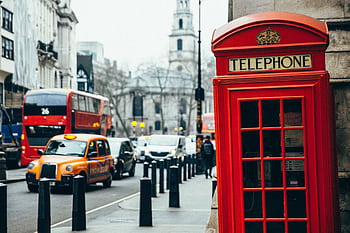 A classic red tele booth with bustling London street background featuring buses and taxis. HD wallpaper