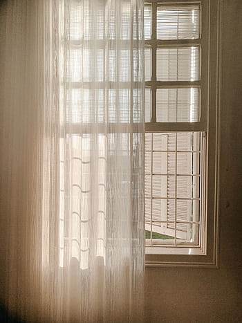 A serene view of sunlight filtering through sheer window curtains, casting soft shadows indoors. HD phone wallpaper