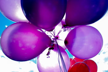 Bright purple balloons floating against a clear blue sky, perfect for celebrations. HD wallpaper