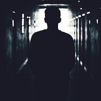 Silhouette of a person standing in a shadowy tunnel, evoking mystery. HD phone wallpaper