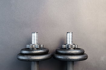 Close-up of two iron dumbbells on a gray background, perfect for strength training . HD wallpaper