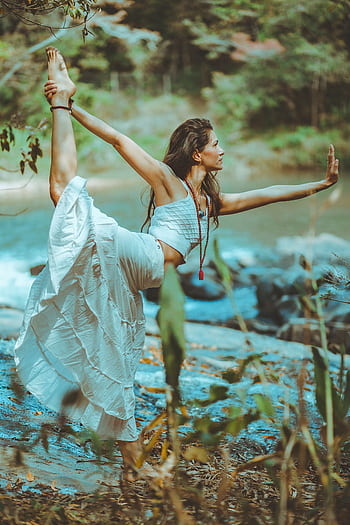 A serene scene of a woman practicing yoga by a que river shore, embodying balance and tranquility. HD phone wallpaper