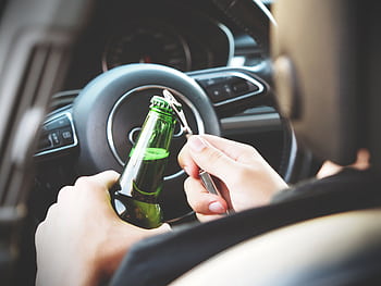 Hands opening a beer bottle inside a car, highlighting the importance of safe driving and awareness of road dangers. HD wallpaper