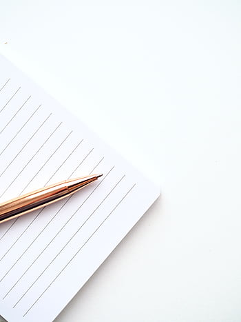 A close-up shot of a gold pen on a lined notepad with a white background, offering ample copyspace. HD phone wallpaper