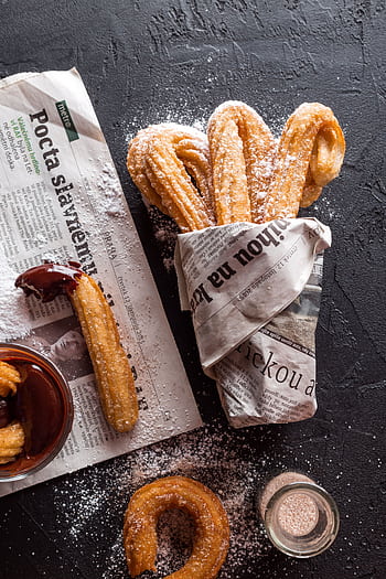 Freshly made churros dusted with sugar, wrapped in newspaper, with chocolate sauce. HD phone wallpaper
