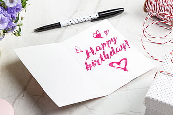 A vibrant birtay card with heart illustrations, surrounded by a pen, flowers, and gift wrap. HD wallpaper