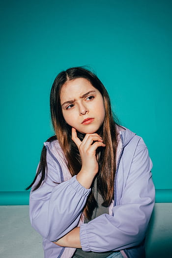 A young girl pondering deeply against a vibrant teal background. HD phone wallpaper