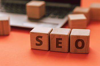 Wooden blocks spelling SEO on a laptop keyboard convey digital marketing concepts. HD wallpaper