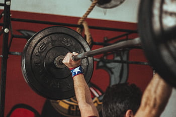 Athlete lifting heavy barbell during strength training session in gym. HD wallpaper