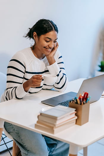 Young woman working from home using laptop and enjoying a cup of coffee. HD phone wallpaper