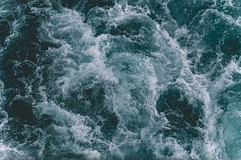 Powerful ocean waves captured from above, showcasing the dynamic movement and blue hues of the sea. HD wallpaper