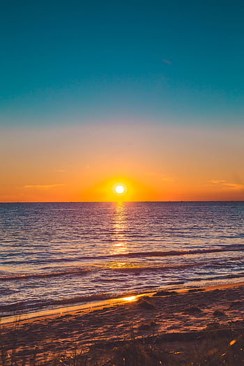 Beautiful sunset over a calm ocean with vibrant sky, perfect for relaxation themes. HD phone wallpaper