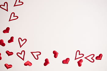 Red hearts scattered on a white background, ideal for Valentine's Day or romantic themes. HD wallpaper