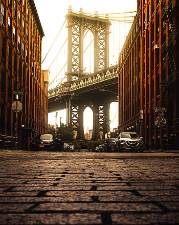 Captured in Dumbo, Brooklyn, this view highlights the iconic Brooklyn Bridge framed by urban architecture at sunset. HD phone wallpaper