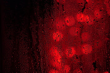 Close-up of raindrops on a red and black surface with bokeh lights creating an abstract, moody effect. HD wallpaper