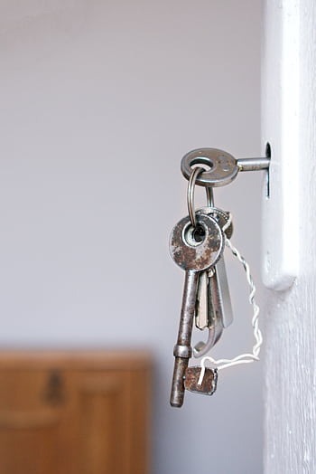 Close-up of vintage keys in a door keyhole with rustic metal and wood textures. HD phone wallpaper