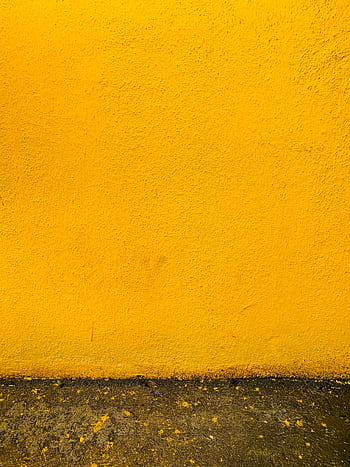 Vibrant yellow stucco wall with a rough texture and concrete base, ideal for backgrounds. HD phone wallpaper