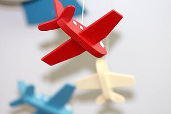 A close-up of colorful wooden airplane toys in a mobile, perfect for nursery décor. HD wallpaper
