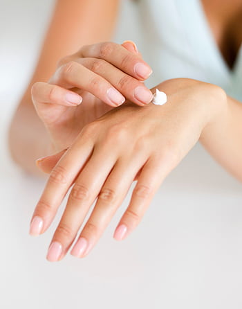 A woman applying cream on her hands, highlighting skincare and self-care concepts. HD phone wallpaper