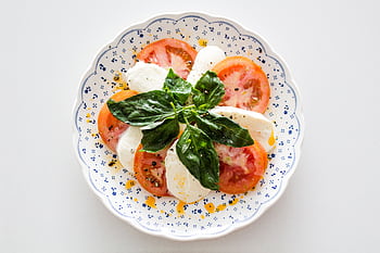 Fresh Caprese salad with tomatoes, mozzarella, and basil on a decorative plate. HD wallpaper