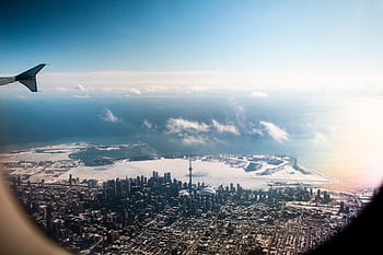 A stunning aerial view of Toronto skyline with the CN Tower and snowy landscape, seen from an airplane. HD wallpaper