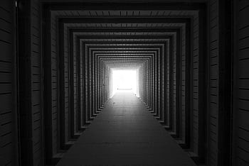 Black and white of a tunnel-like architecture with sunlight illuminating the end. HD wallpaper