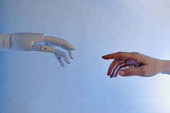 A human hand reaching towards a robotic hand symbolizing technology and connection. HD wallpaper