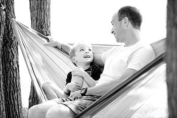 A lovely moment between father and son in a hammock, showcasing family bonding and happiness. HD wallpaper