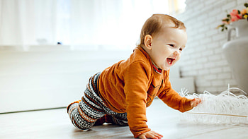 Smiling Cute Baby Is Crawling On Floor Wearing Orange Sweater Playing With White Feather Cute HD wallpaper