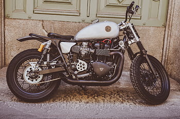 Classic motorcycle parked against a grunge wall, showcasing its sleek vintage design. HD wallpaper