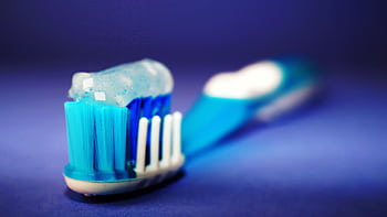 Macro shot of a toothbrush with blue toothpaste and blurred background. HD wallpaper
