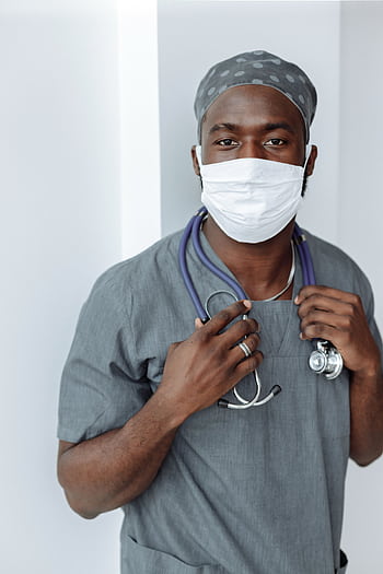 Portrait of a healthcare worker wearing a face mask and scrubs, demonstrating COVID-19 safety measures. HD phone wallpaper
