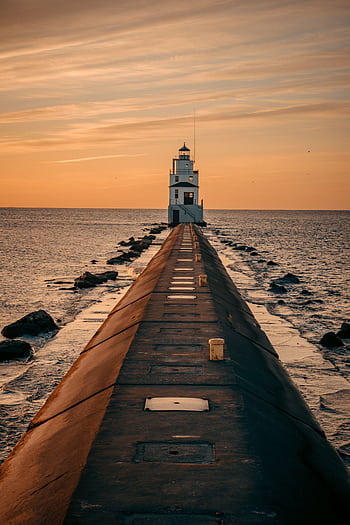 Stunning sunset view of the Manitowoc Breakwater Lighthouse, WI, capturing the tranquil ocean and warm skies. HD phone wallpaper
