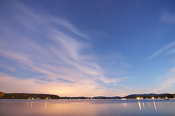Beautiful twilight scene with stars reflecting over calm waters and distant boats. HD wallpaper